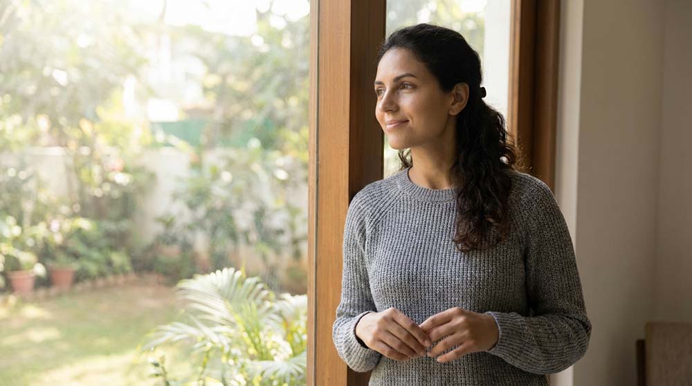Woman standing near window symbolising recovery after pregnancy loss