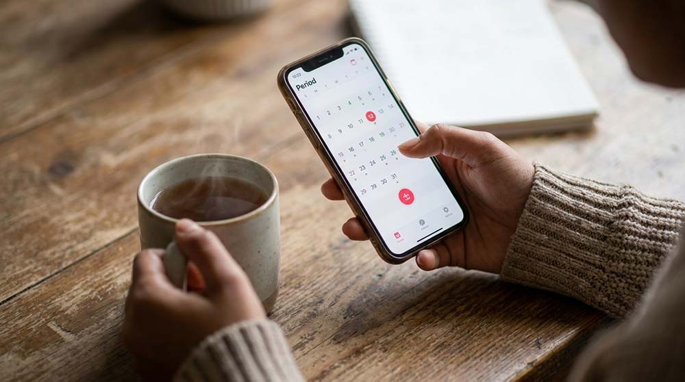Woman tracking menstrual cycle and pregnancy symptoms on calendar app