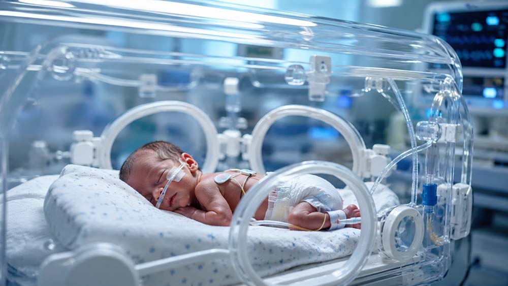 Premature baby receiving specialised NICU care inside hospital incubator unit